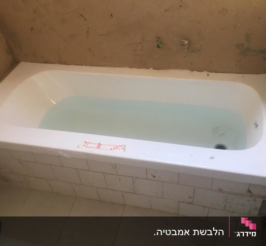 אמבטיה עם מים, קירות לא גמורים, אריחים לבנים